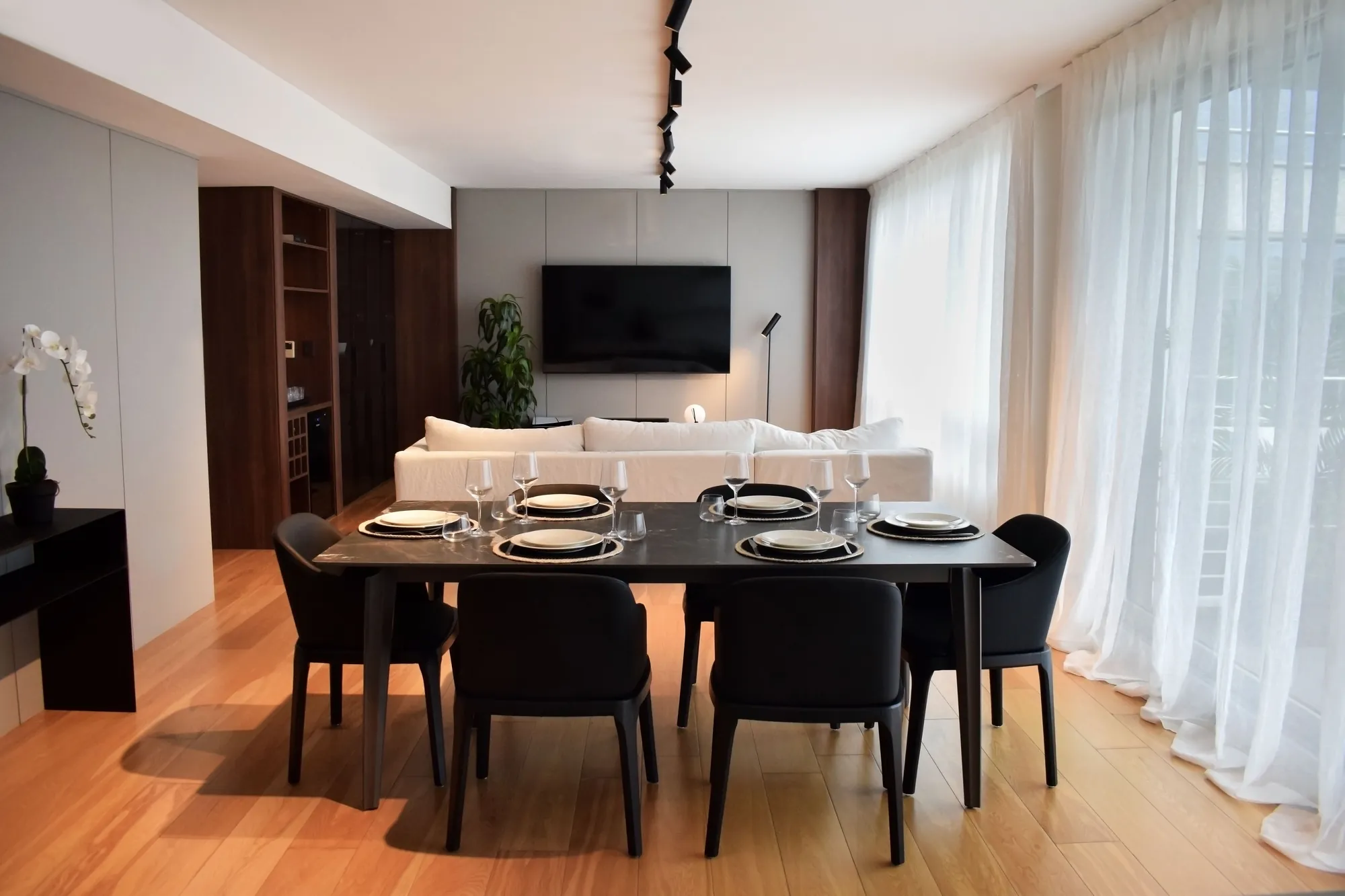 Comedor y living integrados del proyecto Al Río, con mesa oscura y cortinas livianas