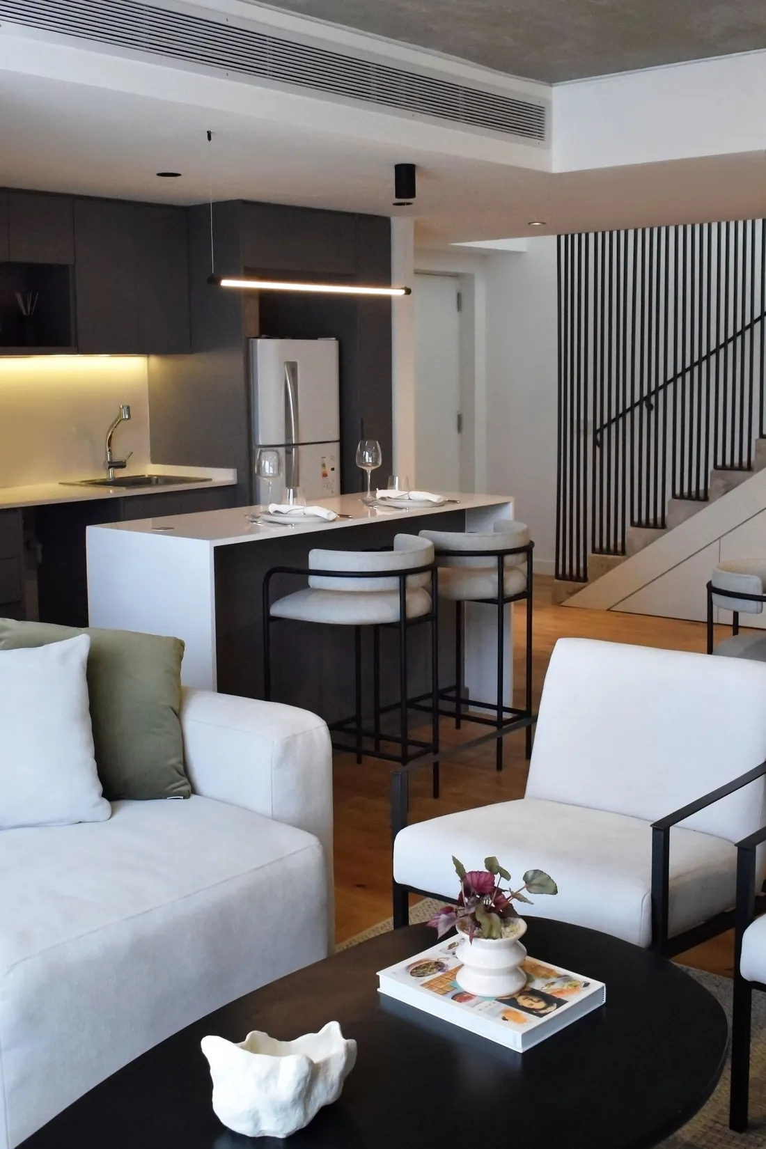 Cocina con isla, banquetas y escalera de fondo